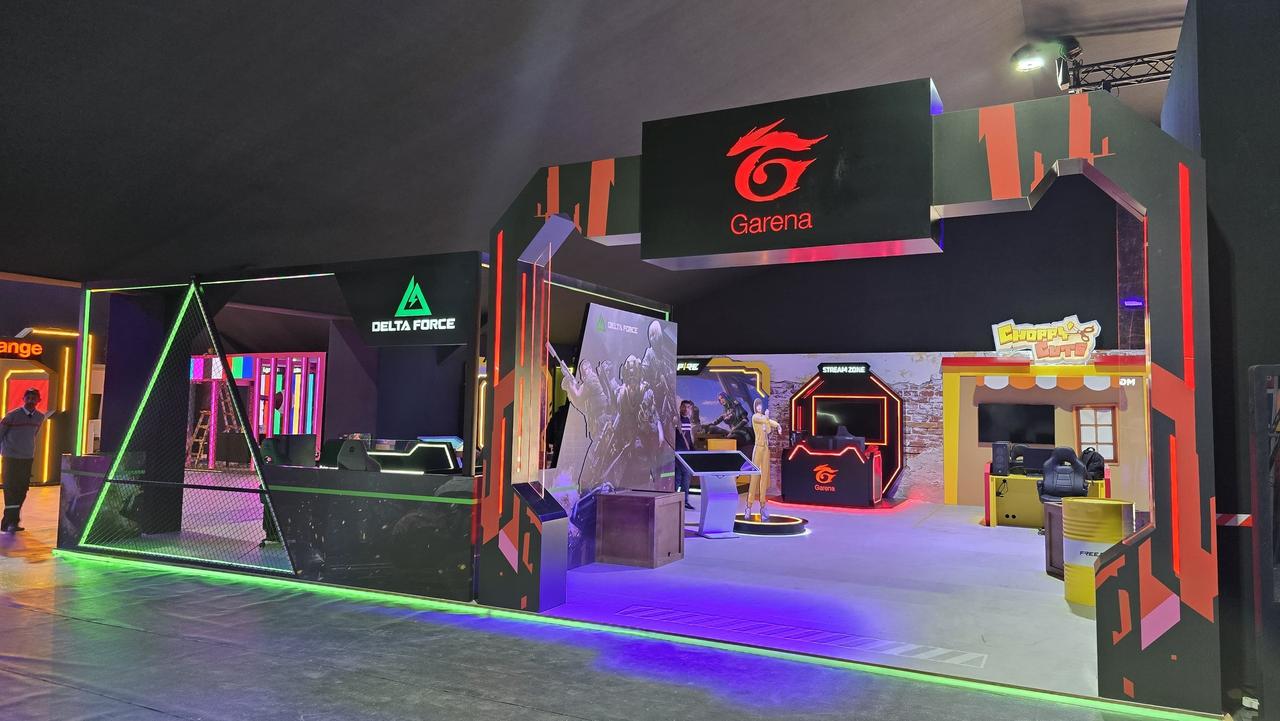 Stand Garena livré, de nuit : arche lumineuse et enseigne Garena, triangle lumineux de la zone Delta Force.
