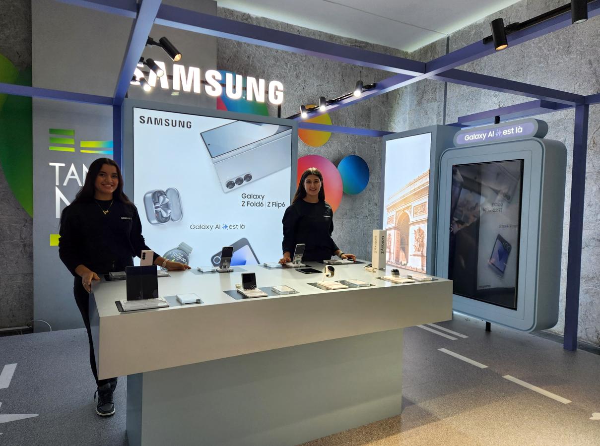 Deux hôtesses derrière la table de démonstration du corner Samsung Galaxy AI, totem écran à droite.
