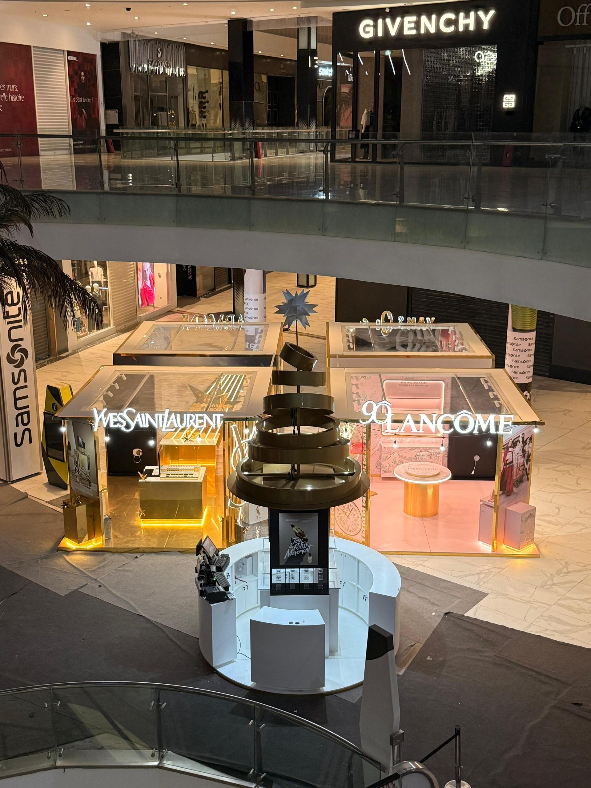 Le village livré, de nuit : quatre cabines dorées autour d’un kiosque central, dans l’atrium.