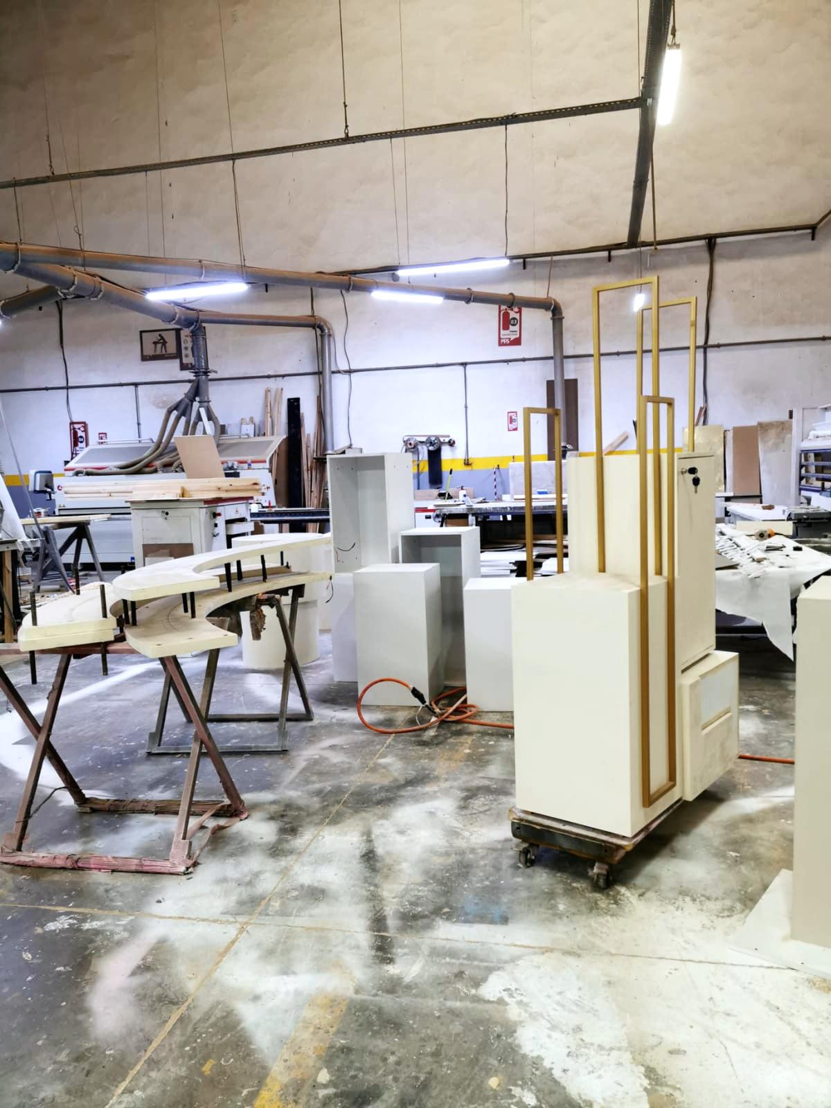 L’atelier de menuiserie : présentoirs à cadres dorés et éléments laqués en cours d’assemblage.